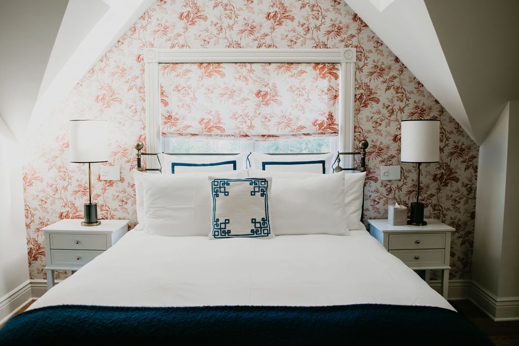 Un dormitorio con una cama grande, dos mesitas de noche y un estampado de papel tapiz floral.
