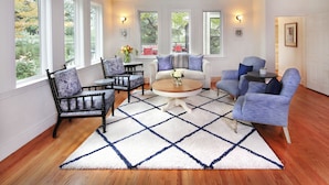 A room with a large window, a round table, and two blue armchairs. - Grape Leaf Inn (Healdsburg)