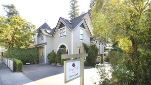 A two-story house with a gabled roof, a front entrance, and a driveway leading to a gated parking area. - Grape Leaf Inn (Healdsburg)