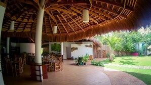A covered outdoor area with wooden furniture and a thatched roof. - Vanilla Sky Dive Resort (Panglao)