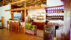 A bar area with wooden beams, a bar counter, seating, and shelves of bottles. - Vanilla Sky Dive Resort (Panglao)