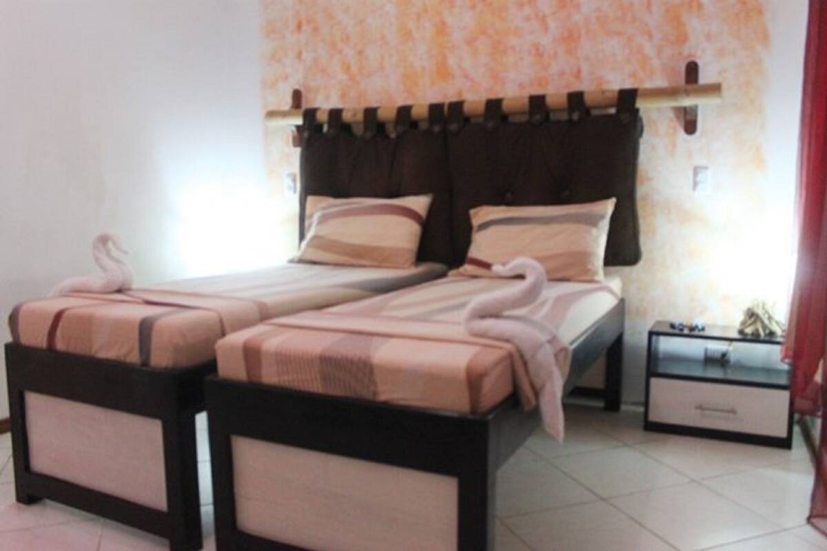 Una cama doble con cabecera, dos mesitas de noche y una mesilla.