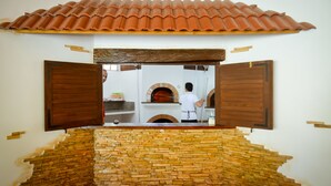 A view through a wooden-framed window into a kitchen area with a brick wall and a tiled roof. - Vanilla Sky Dive Resort (Panglao)
