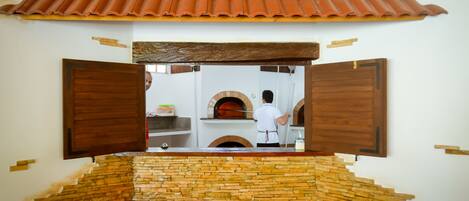 A view through a wooden-framed window into a kitchen area with a brick wall and a tiled roof.