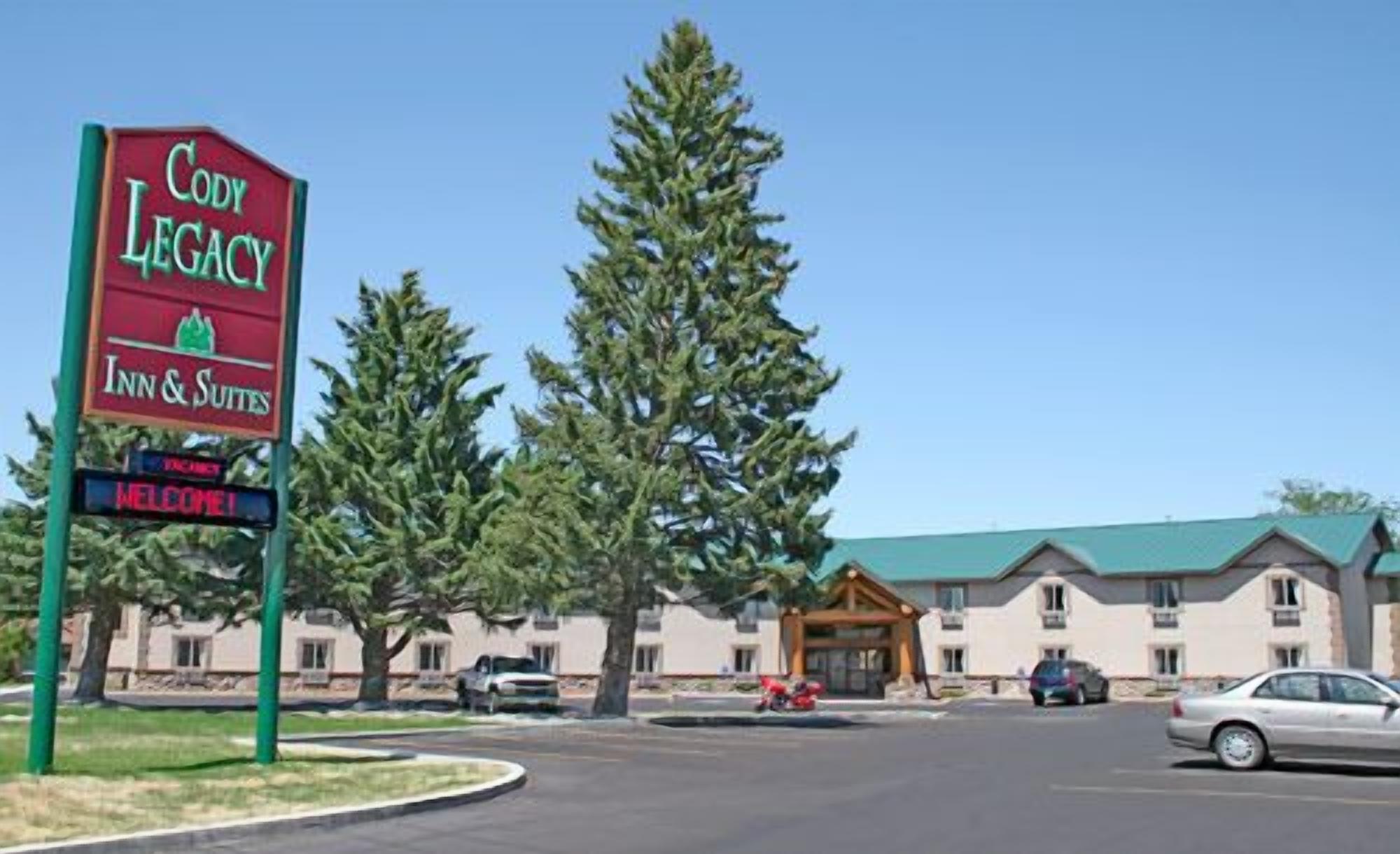 Placa de hotel com 'Cody Legacy Inn & Suites' e a mensagem 'Bem-vindo!'.