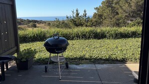 A barbecue grill in a backyard with a view of the ocean.