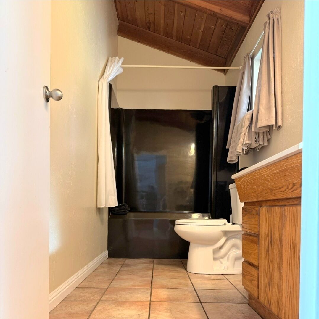 Ein Badezimmer mit Dusche, Toilette und Holzwaschtisch.