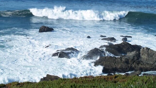 A coastal scene with waves crashing against rocks.