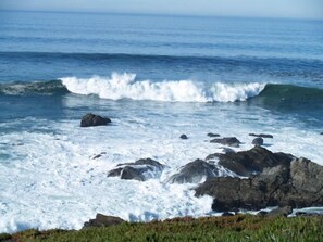 Paisaje costero con olas rompiendo sobre las rocas.
