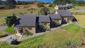 A row of three single-story houses with sloped roofs, a covered outdoor seating area, and a view of the ocean.