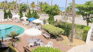 Een zwembadterras van een resort met houten planken, ligbedden en parasols.