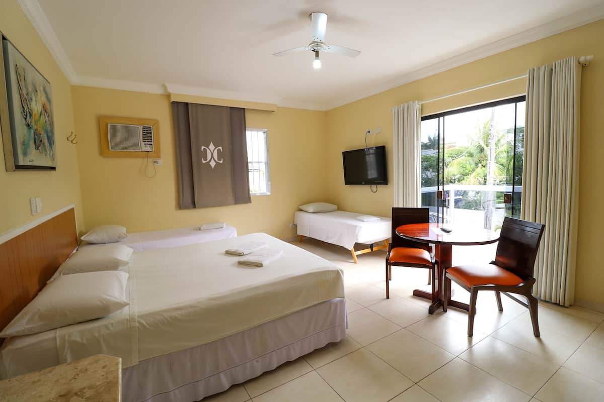 Habitación de hotel con cama, escritorio, silla, televisor y ventana con cortinas.