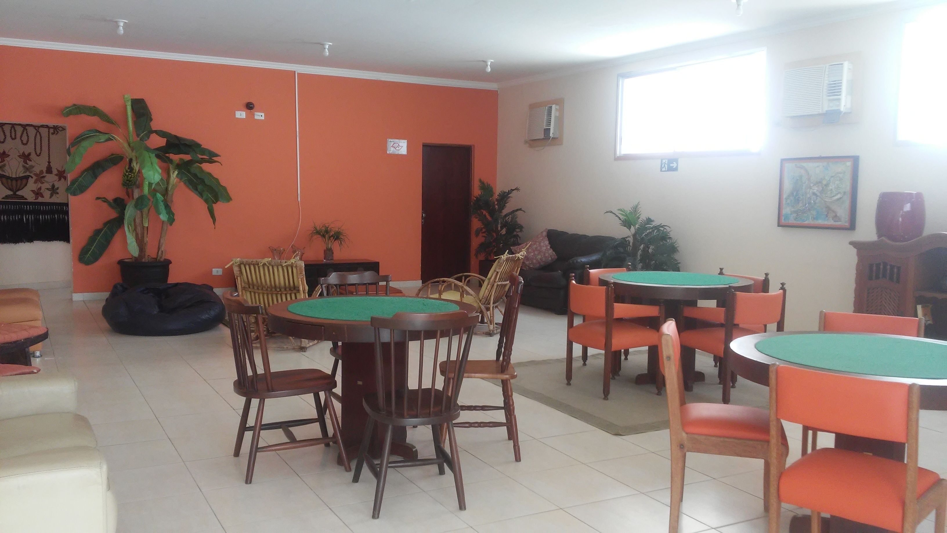 A dining area with wooden tables and chairs, a potted plant, and a sofa.