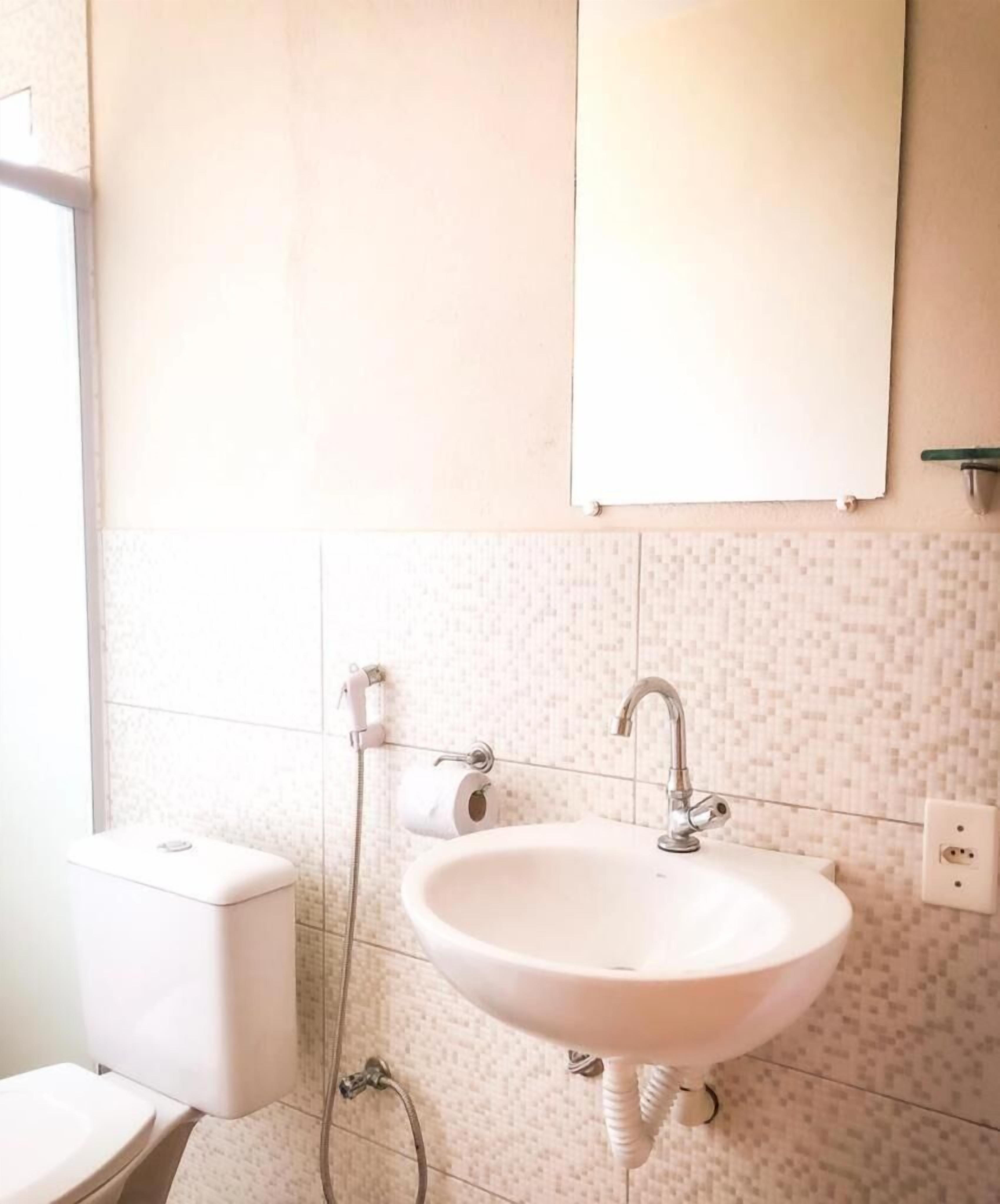 Un baño con lavamanos, inodoro y ducha blancos.