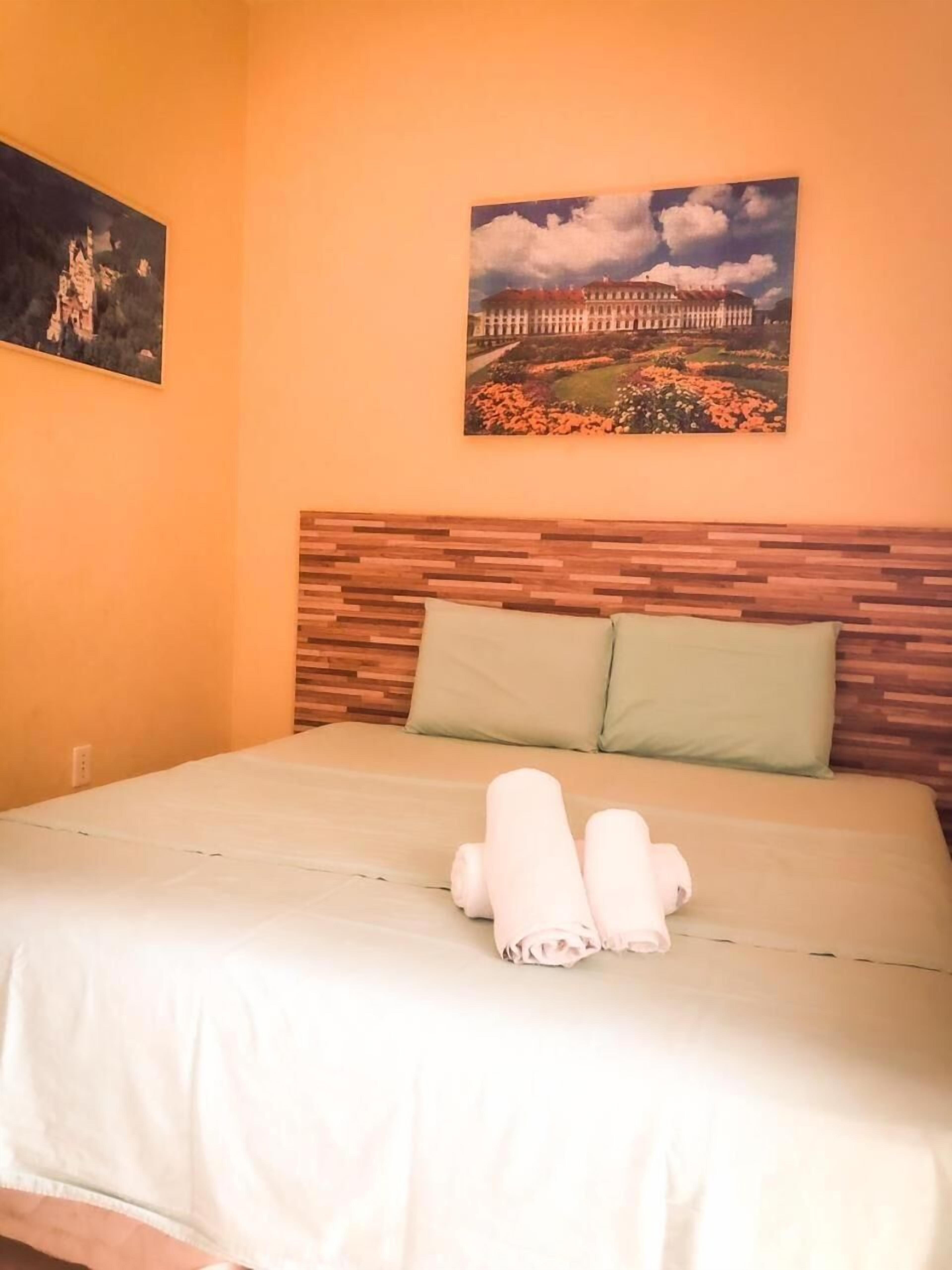 A hotel room with a bed, two pillows, and a painting on the wall.