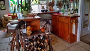 Une cuisine équipée d’un meuble à bouteilles, un coin repas avec un canapé, et un panneau indiquant que le club de golf situé près du volcan est ouvert à tous.