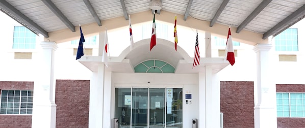 A building entrance with multiple flags, a glass door, and a clock above the door.