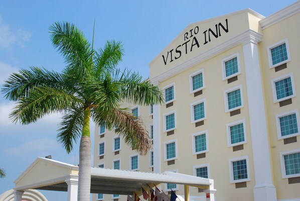 A hotel named Rio Vista Inn with a clear view of its facade, multiple windows, and a palm tree in the foreground.