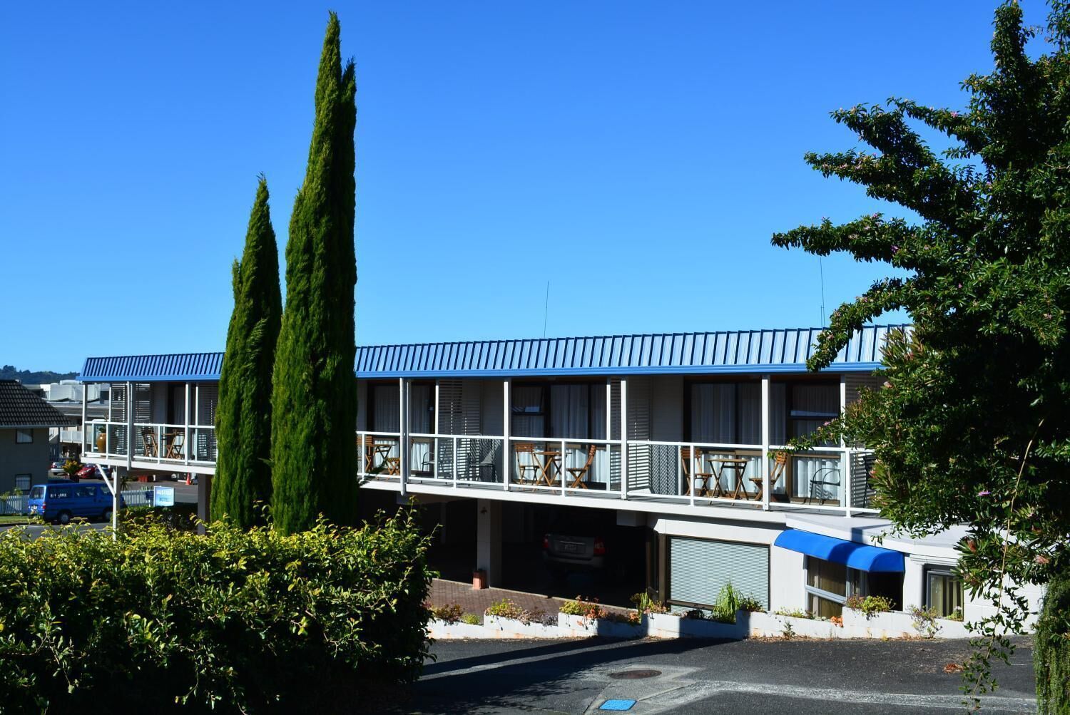 Un edificio de dos pisos con un balcón y un área de estacionamiento techada.