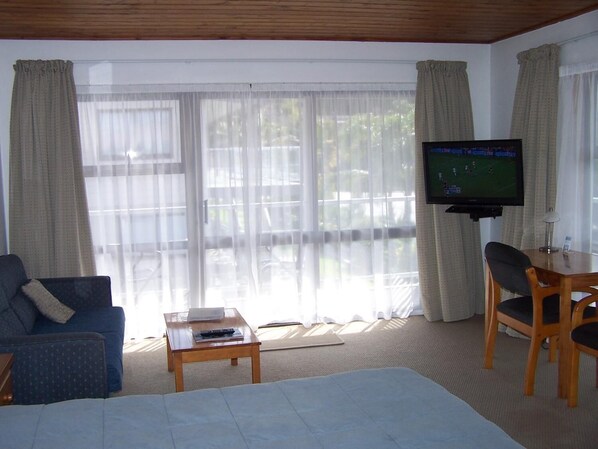 Une chambre d’hôtel comprenant un lit, un téléviseur posé sur un meuble, un bureau avec une chaise et un canapé.