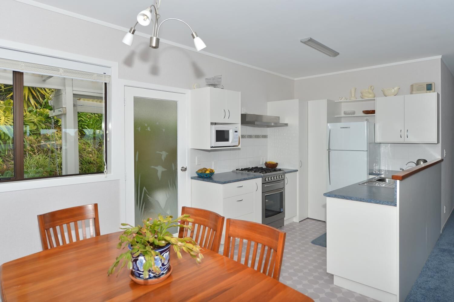 A modern kitchen with white cabinets, a gas stove, a microwave, and a refrigerator.