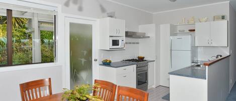 A modern kitchen with white cabinets, a gas stove, a microwave, and a refrigerator.