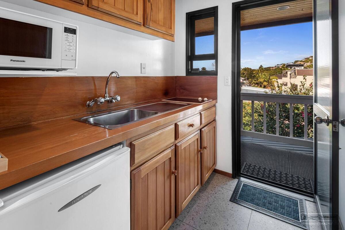 A kitchen with wooden cabinets, a stainless steel sink, and a built-in microwave.