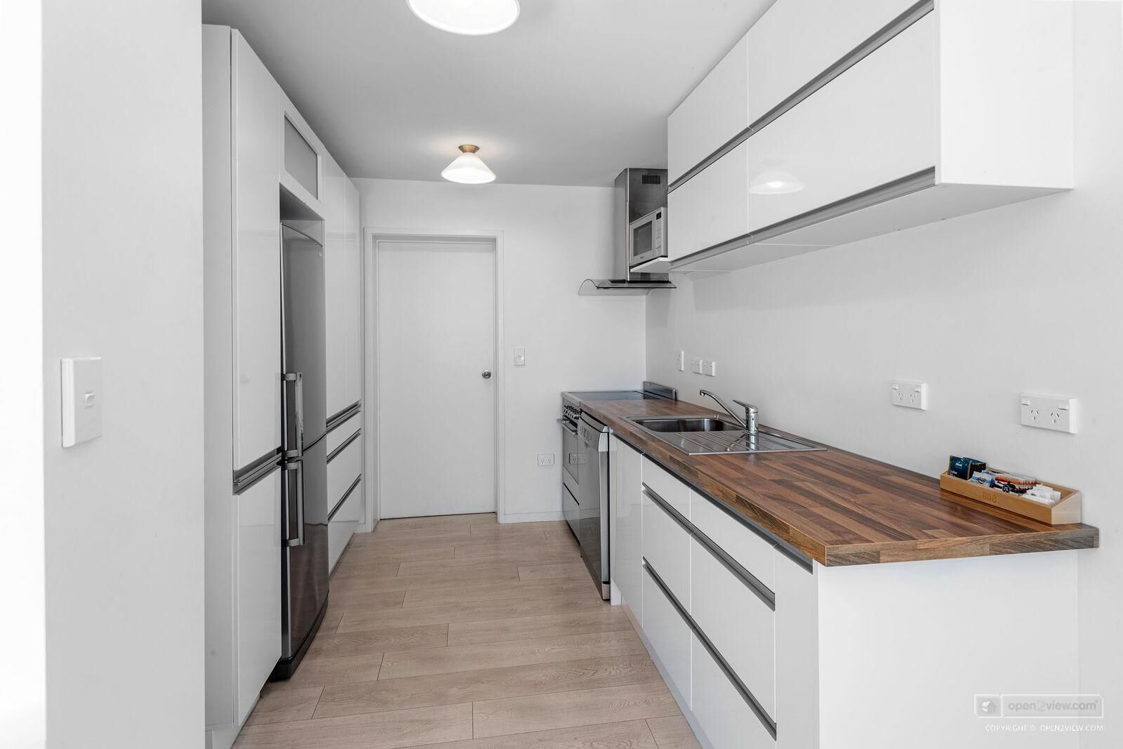 A modern kitchen with white cabinetry, a wooden countertop, and stainless steel appliances.