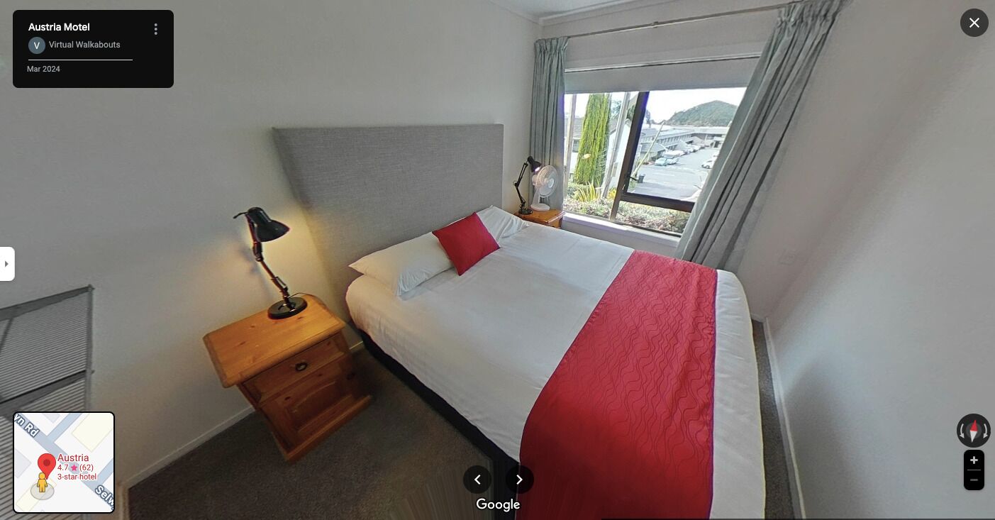 Une chambre d’hôtel trois étoiles comprenant un lit, une table de chevet, une lampe et une fenêtre donnant sur un paysage agréable.