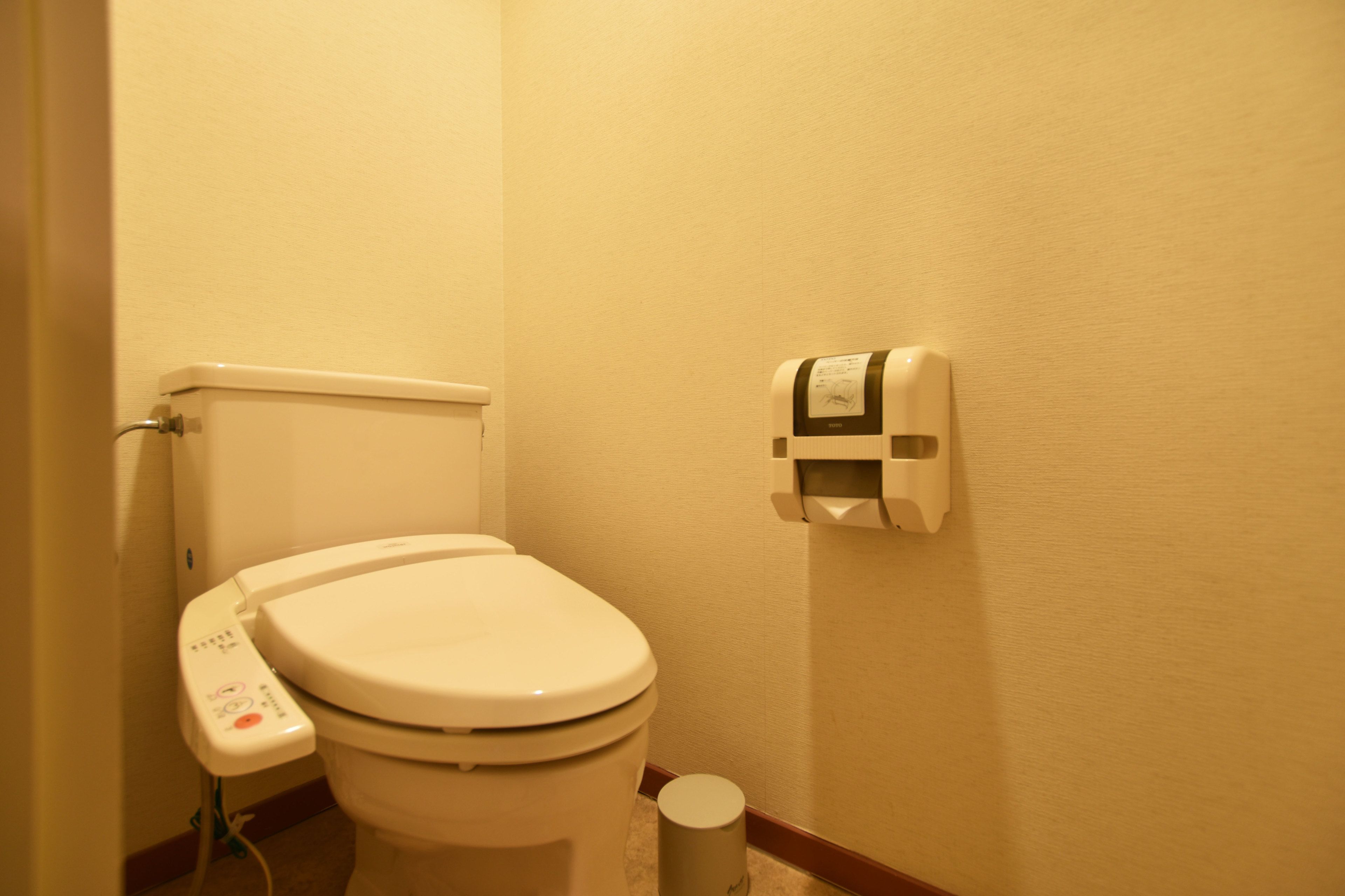 Une salle de bain d’hôtel standard, équipée de toilettes, d’un bidet et d’une poubelle.