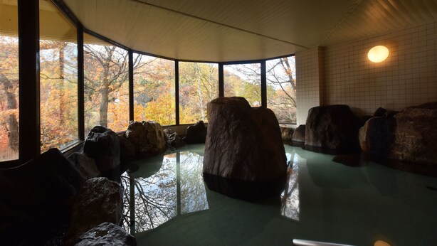 Una habitación con ventanas amplias, piso de baldosas y varias rocas grandes.