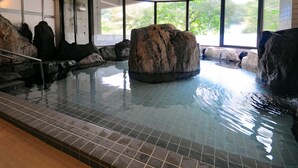 Una piscina interior con grandes formaciones rocosas y suelo de baldosas.