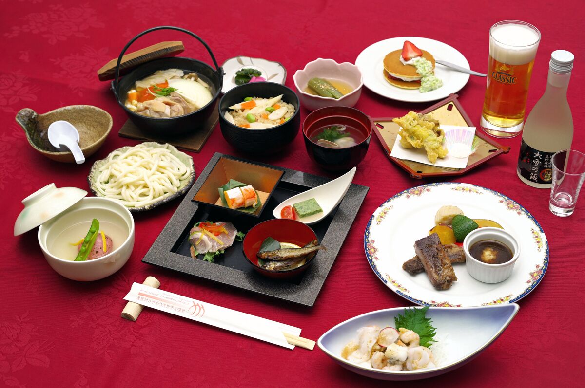 A variety of Japanese dishes including sushi, ramen, and tempura, along with a bottle of sake and a glass of beer.