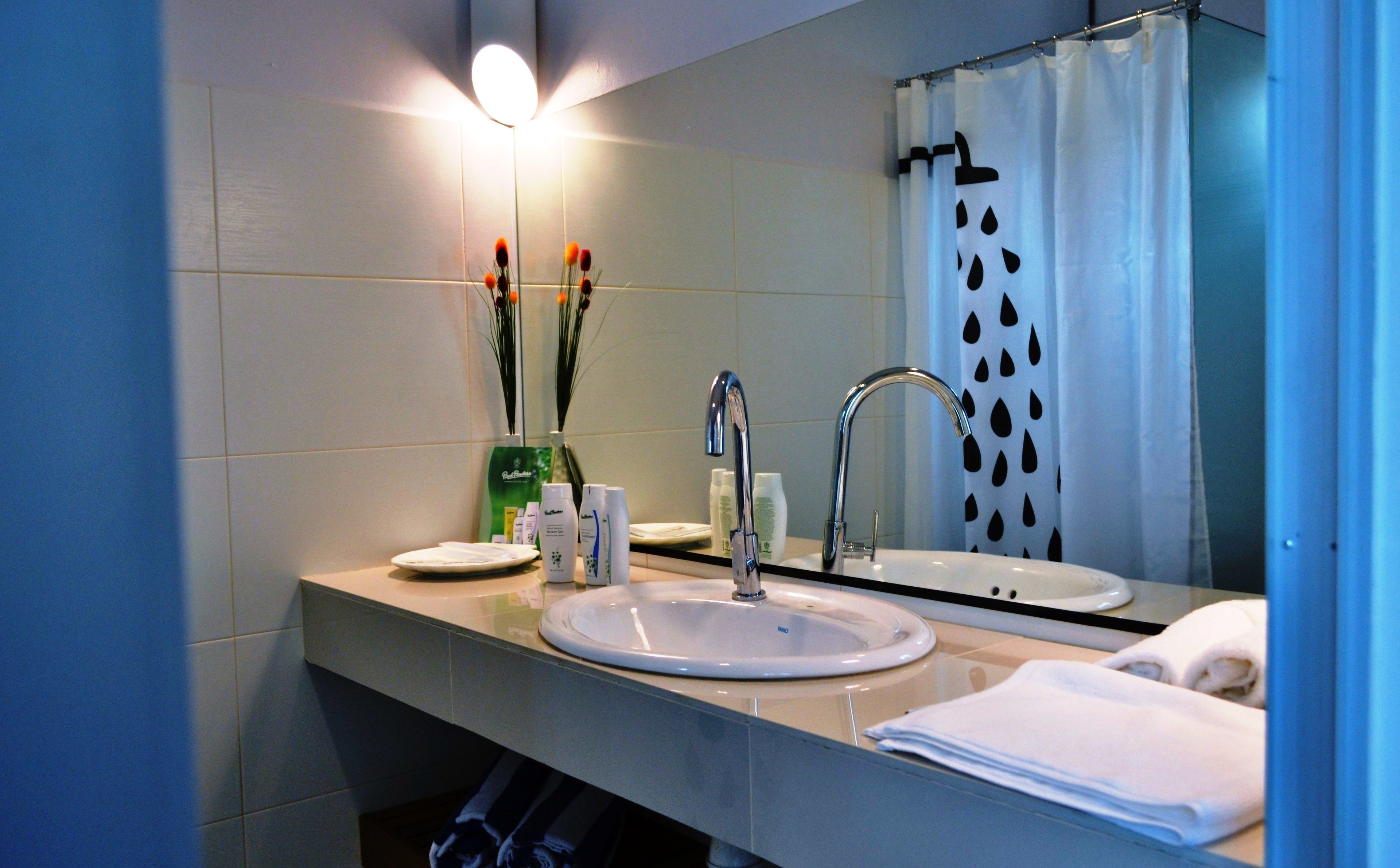 A bathroom with a sink, mirror, and shower curtain.