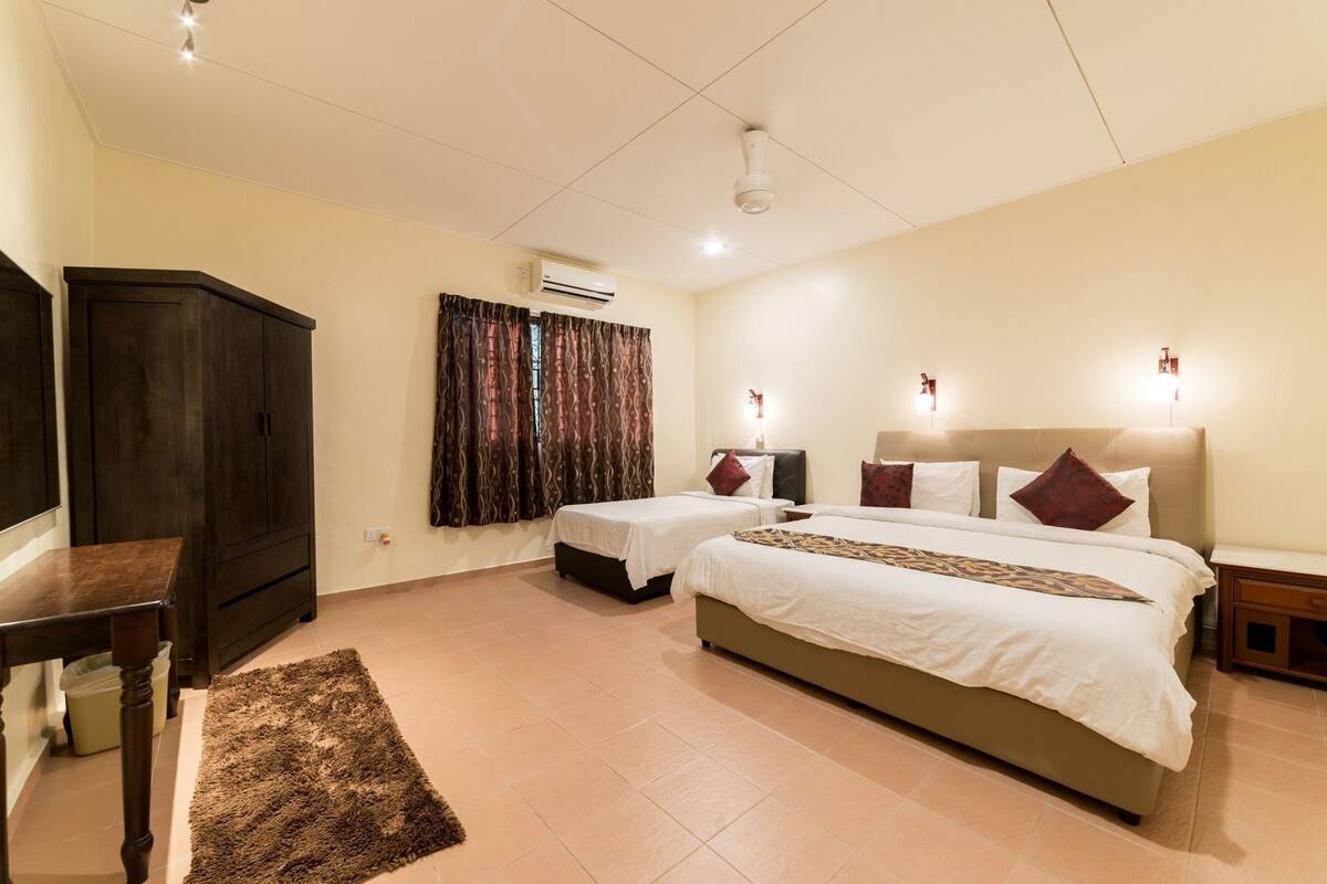 A hotel room with two beds, a wardrobe, an air conditioning unit, and a television.