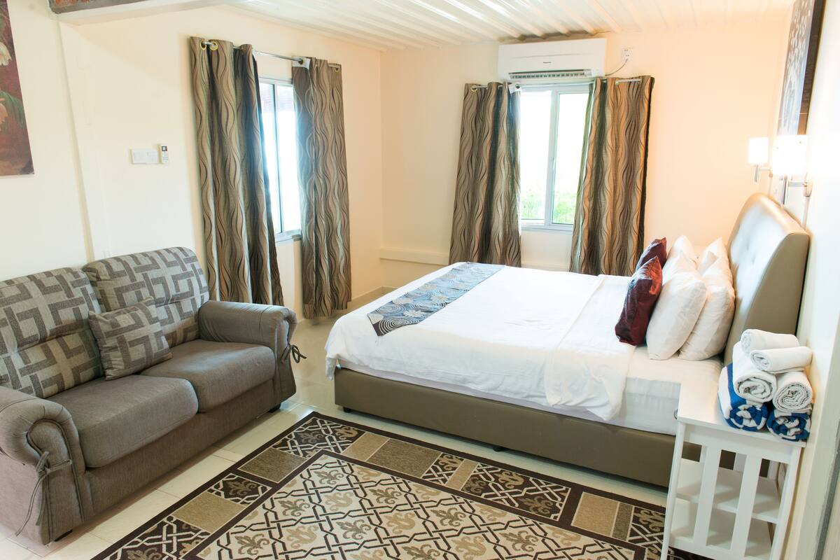 A bedroom with a bed, a sofa, and a small table with towels.