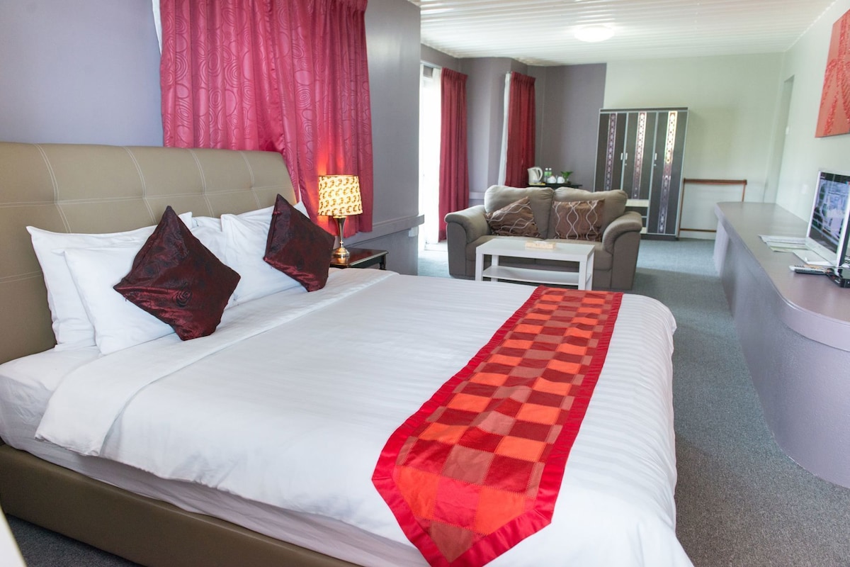 A hotel room with a bed, a desk, a chair, and a wardrobe.