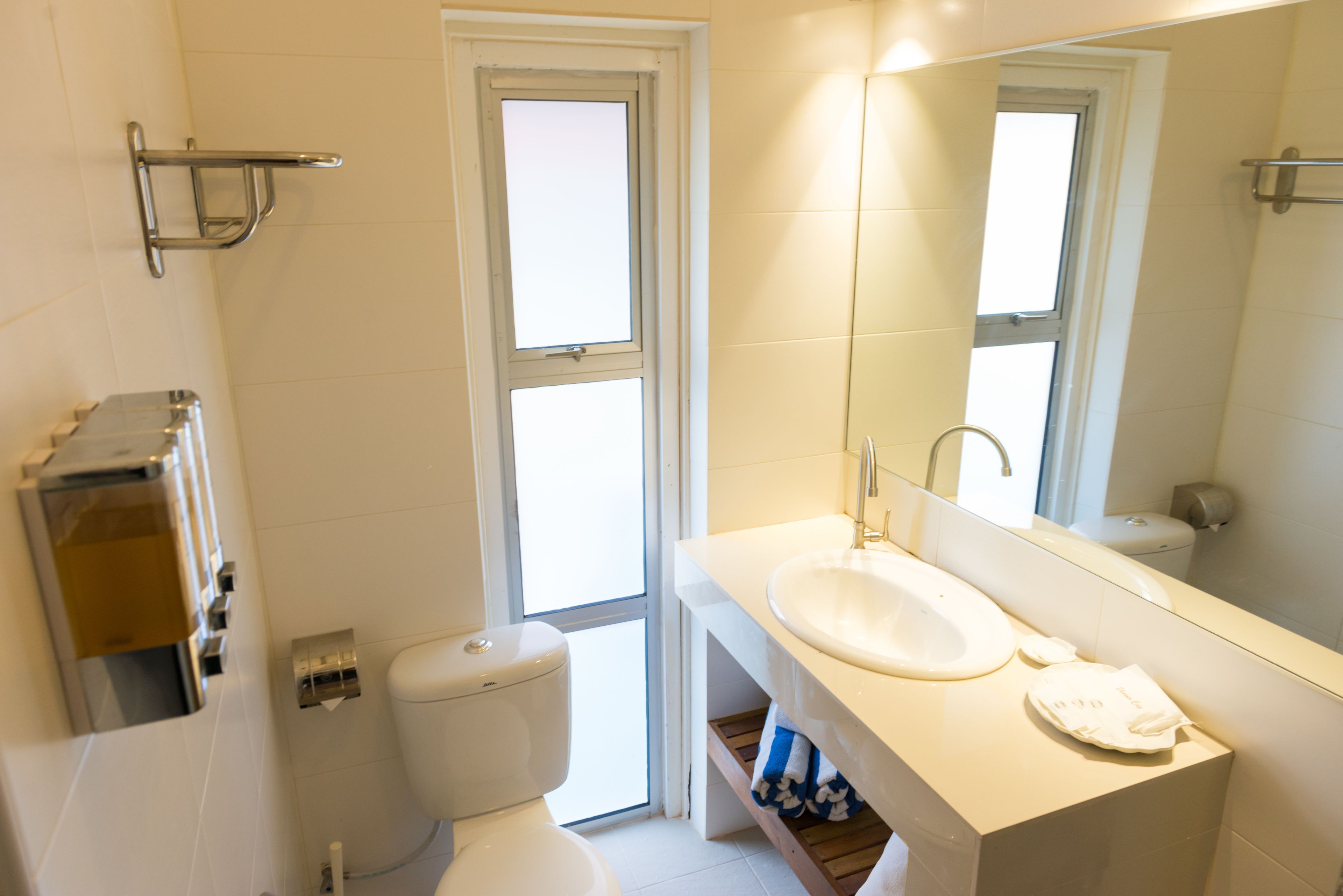 A bathroom with a toilet, sink, and mirror.