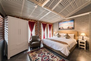 Un dormitorio con una cama grande, un armario, una silla y un cuadro en la pared.