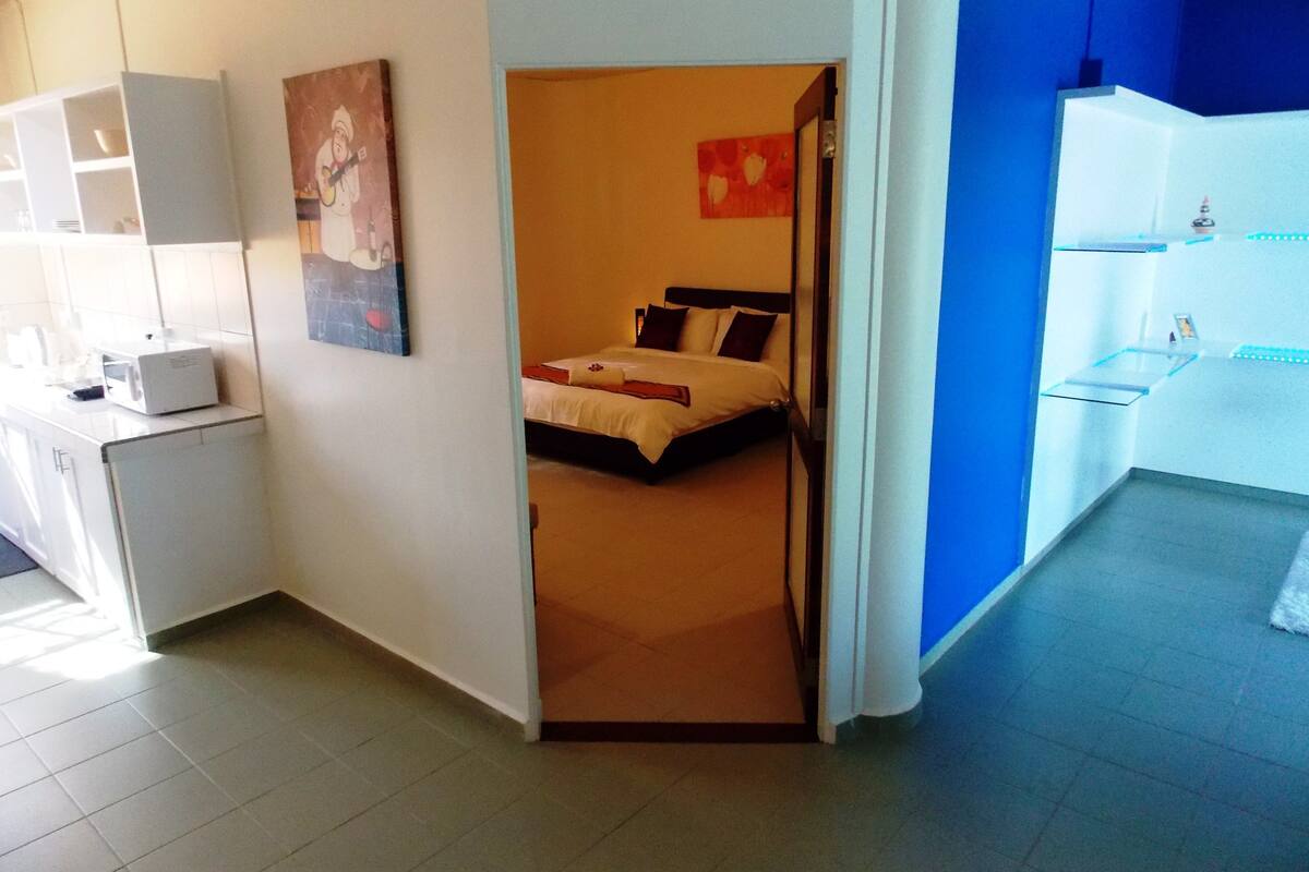 A hotel room with a bed, a desk, and a kitchenette.