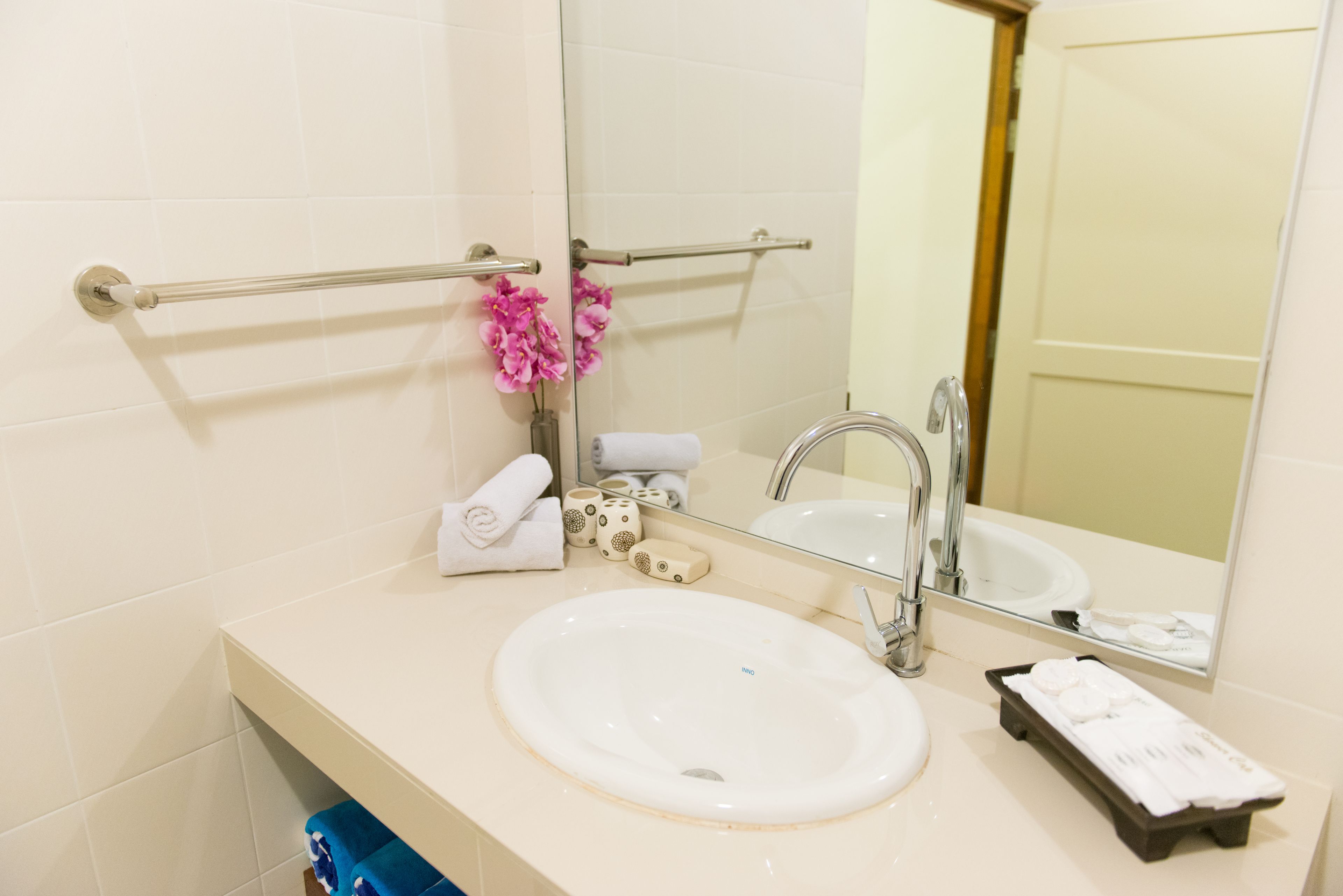 A bathroom with a white sink, a mirror, a towel rack, and a small shelf with toiletries.