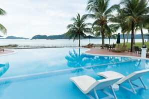 A pool with lounge chairs, palm trees, and a view of the sea. - The Ocean Residence Langkawi (Langkawi)