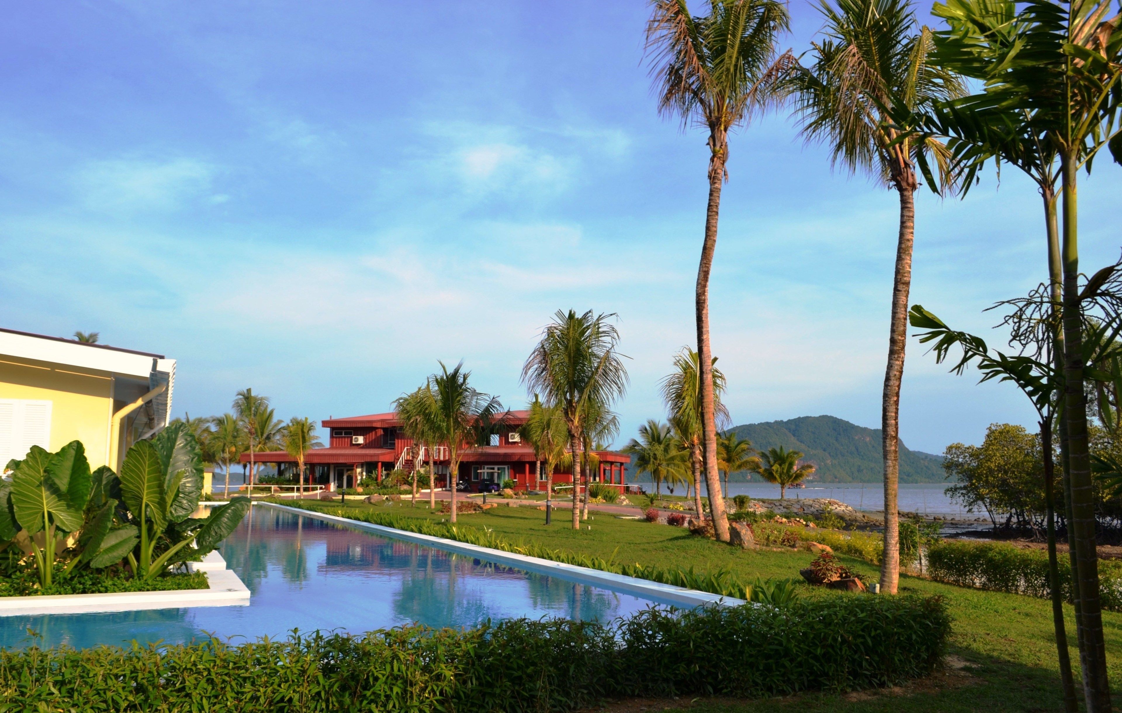 A pool area with a clear view of a red building and palm trees.
