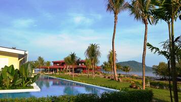 A pool area with a clear view of a red building and palm trees.