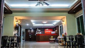 A hotel lobby with a reception desk, seating area, and a ceiling fan. - Airport Resident 2 (Chiang Mai)