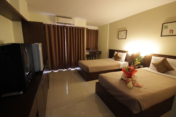 A hotel room with two beds, a desk, a TV, and an air conditioning unit. - Airport Resident 2 (Chiang Mai)