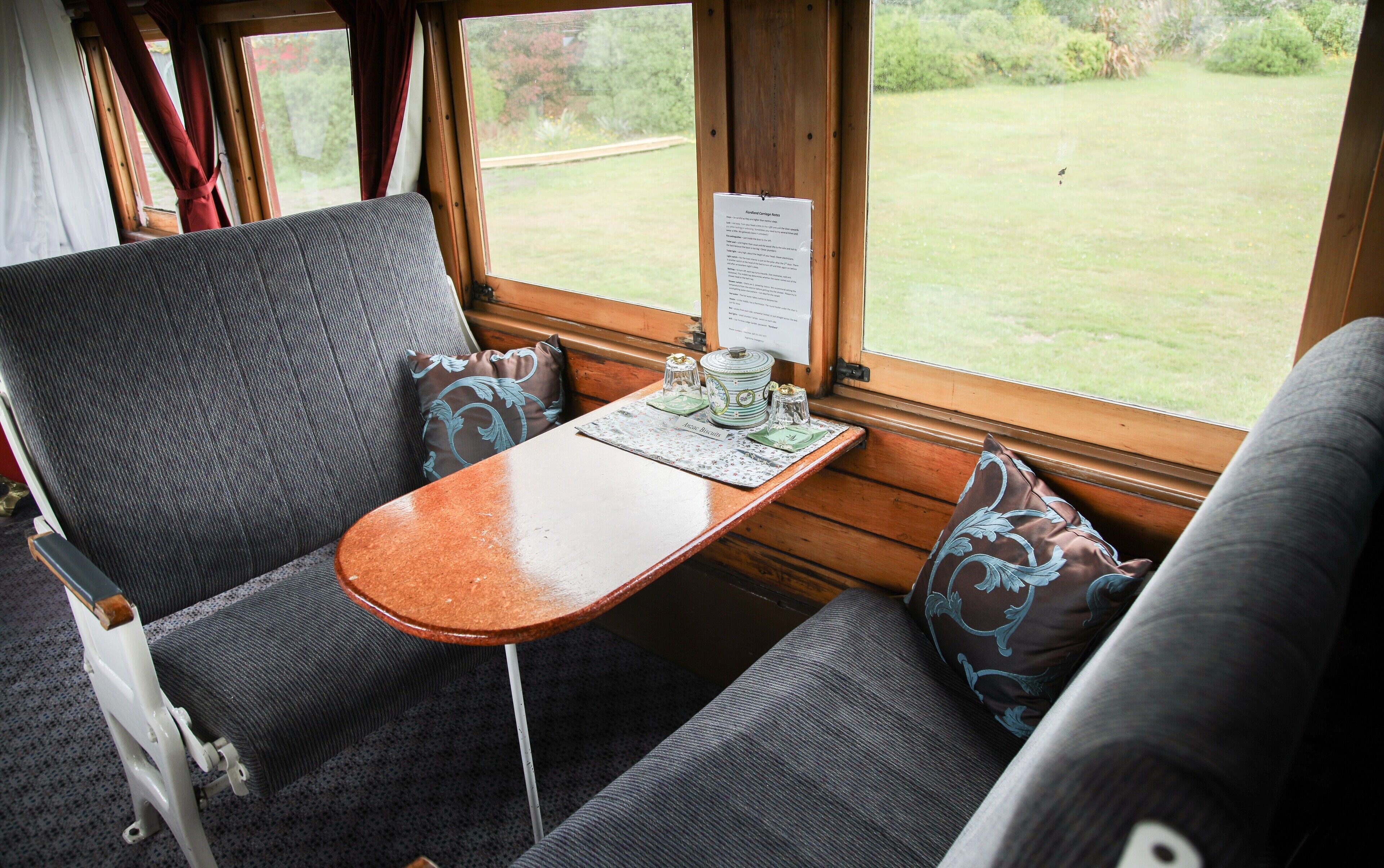 A cozy seating area with a table, two chairs, and a window with a view of a grassy field.