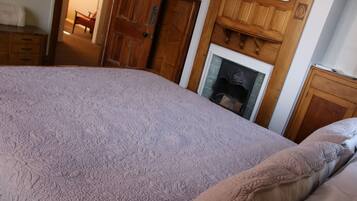 A bedroom with a large bed, wooden headboard, and a fireplace.