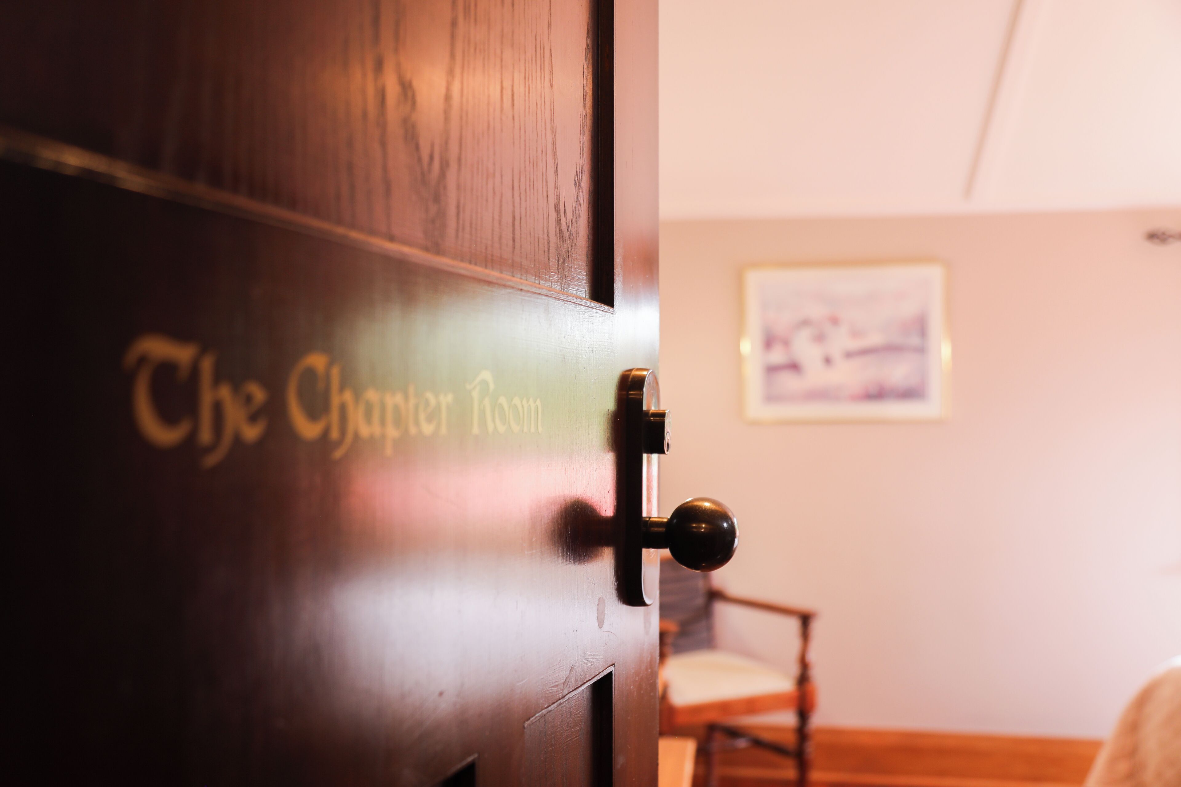 Una puerta de madera con un tirador de latón y las palabras "The Chamber Room" grabadas.
