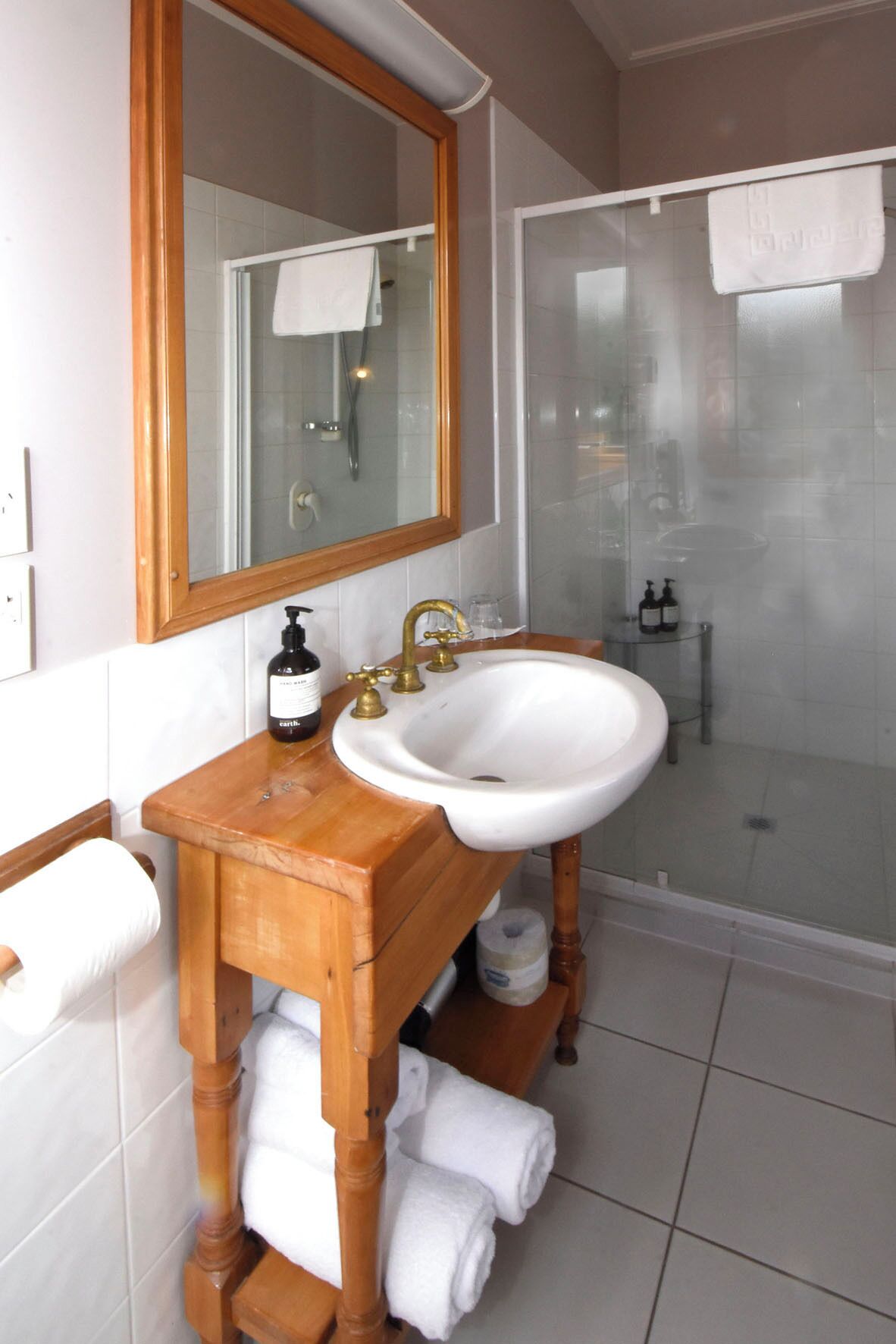 A bathroom with a wooden vanity, white sink, and a glass-enclosed shower.